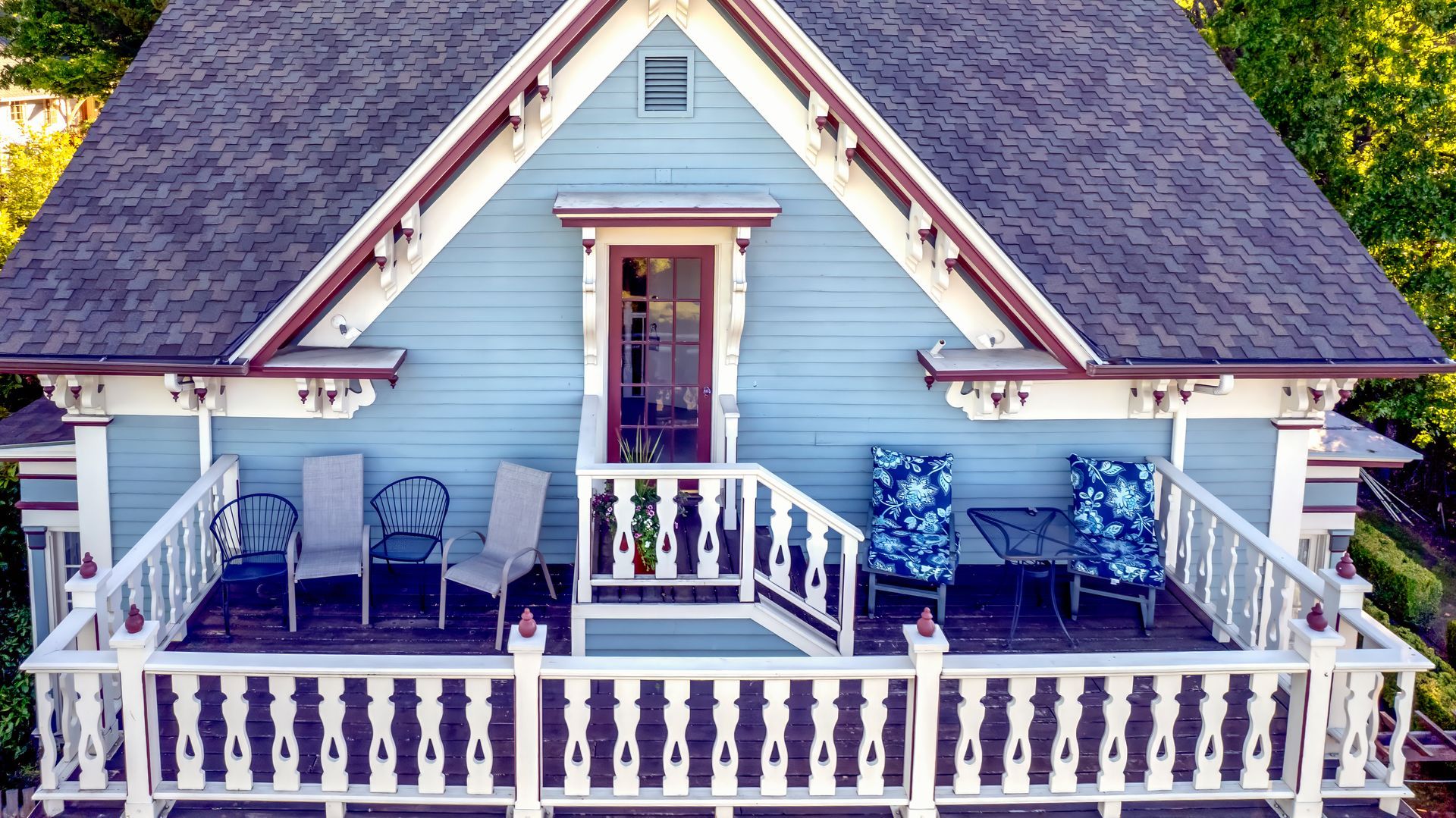 An aerial view of a blue house with a porch and chairs