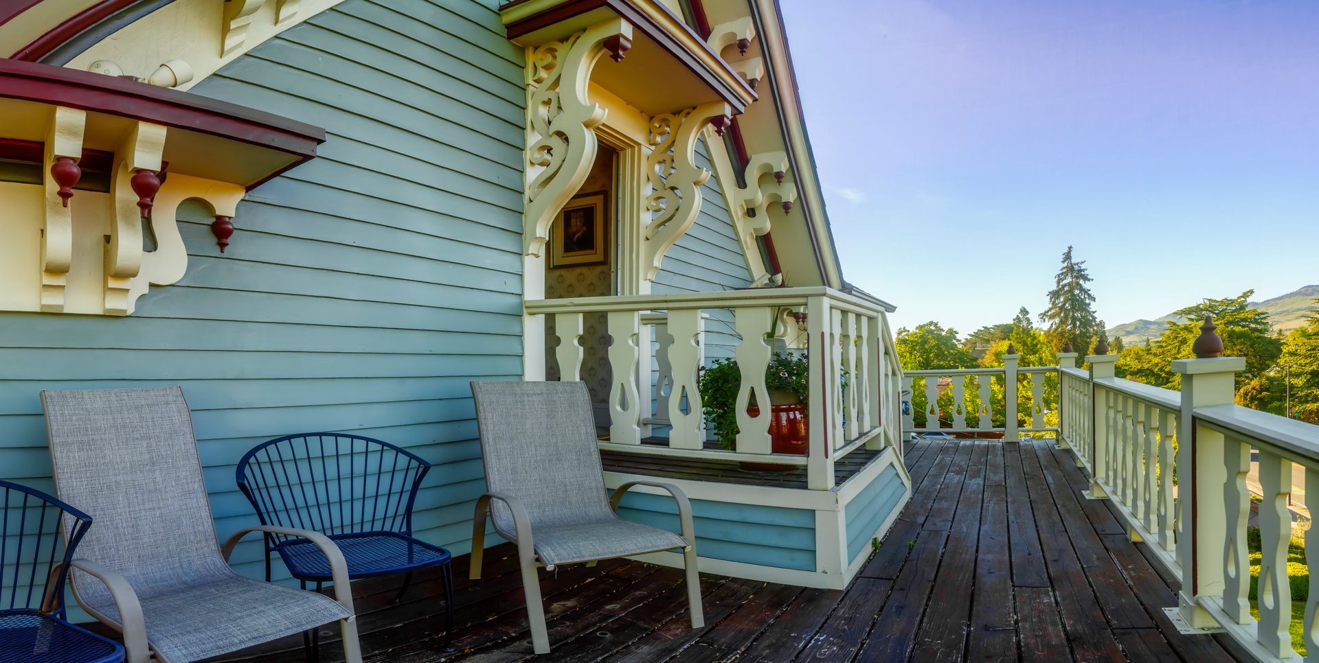 A balcony with chairs and a bench on the side of a house.