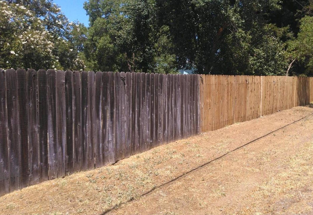 A wooden fence is sitting next to a dirt road.