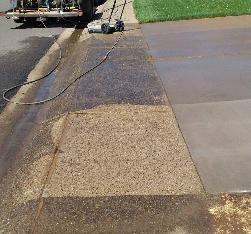 A concrete sidewalk is being cleaned by a truck