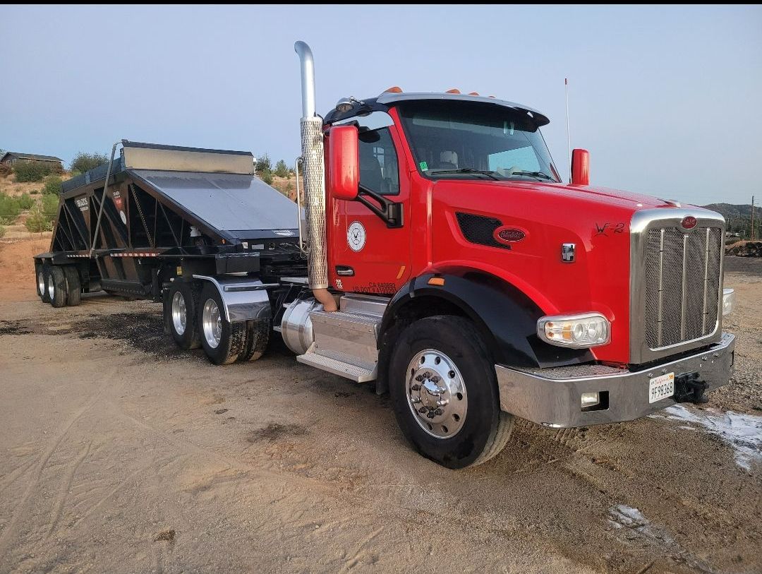 A row of yellow tractors are parked in a dirt field.
