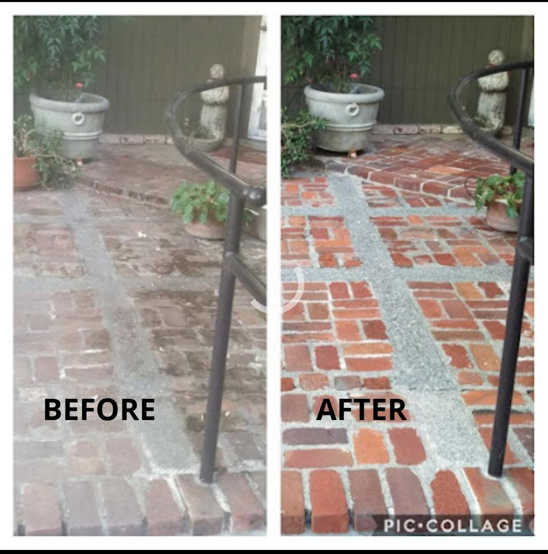 A man is spraying water on a wooden deck next to a swimming pool.