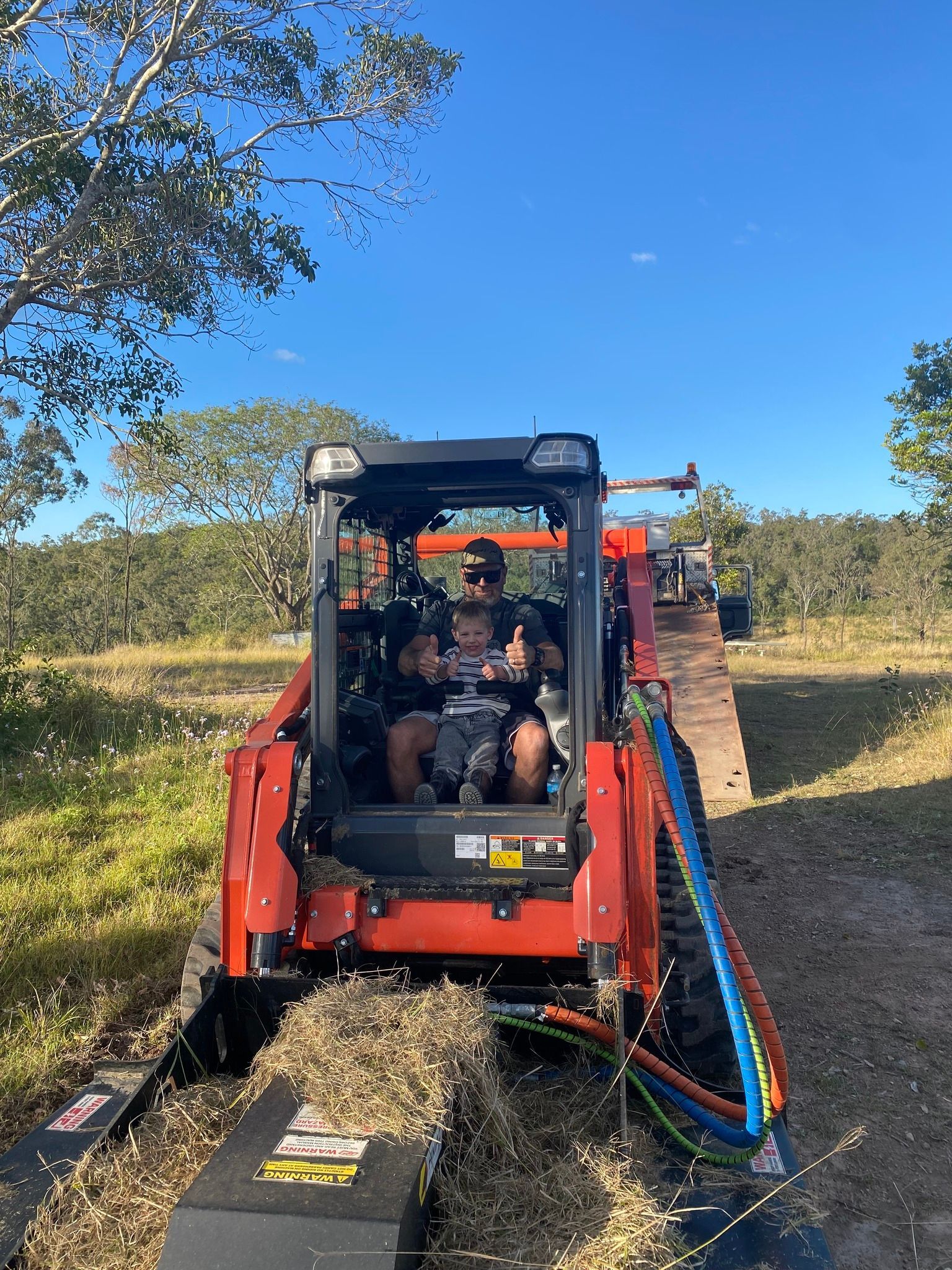 Man Operating Orange Skid Steer With Attached Mulcher, Outdoors. Thumbs Up — Slash Mulch Co in Googa Creek, QLD