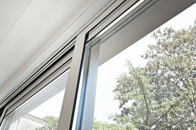 Open sliding window with white frame, showing trees outside.
