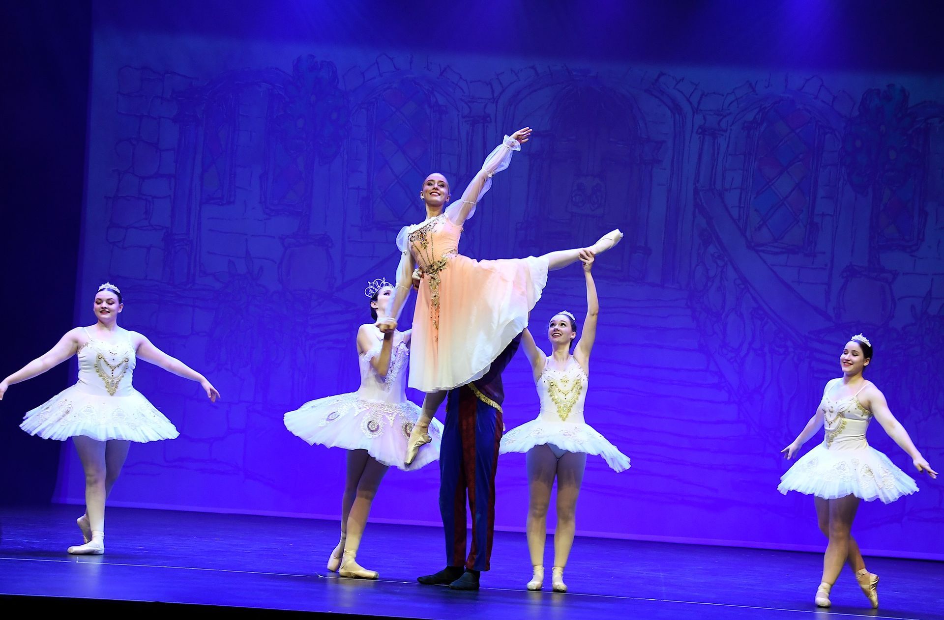 A group of ballet dancers are performing on a stage.