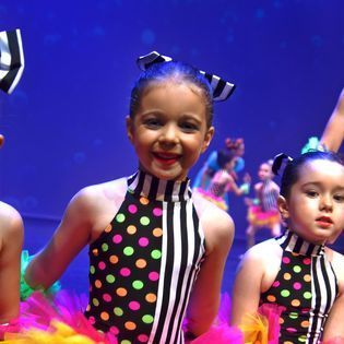 A group of young girls are dancing on a stage.