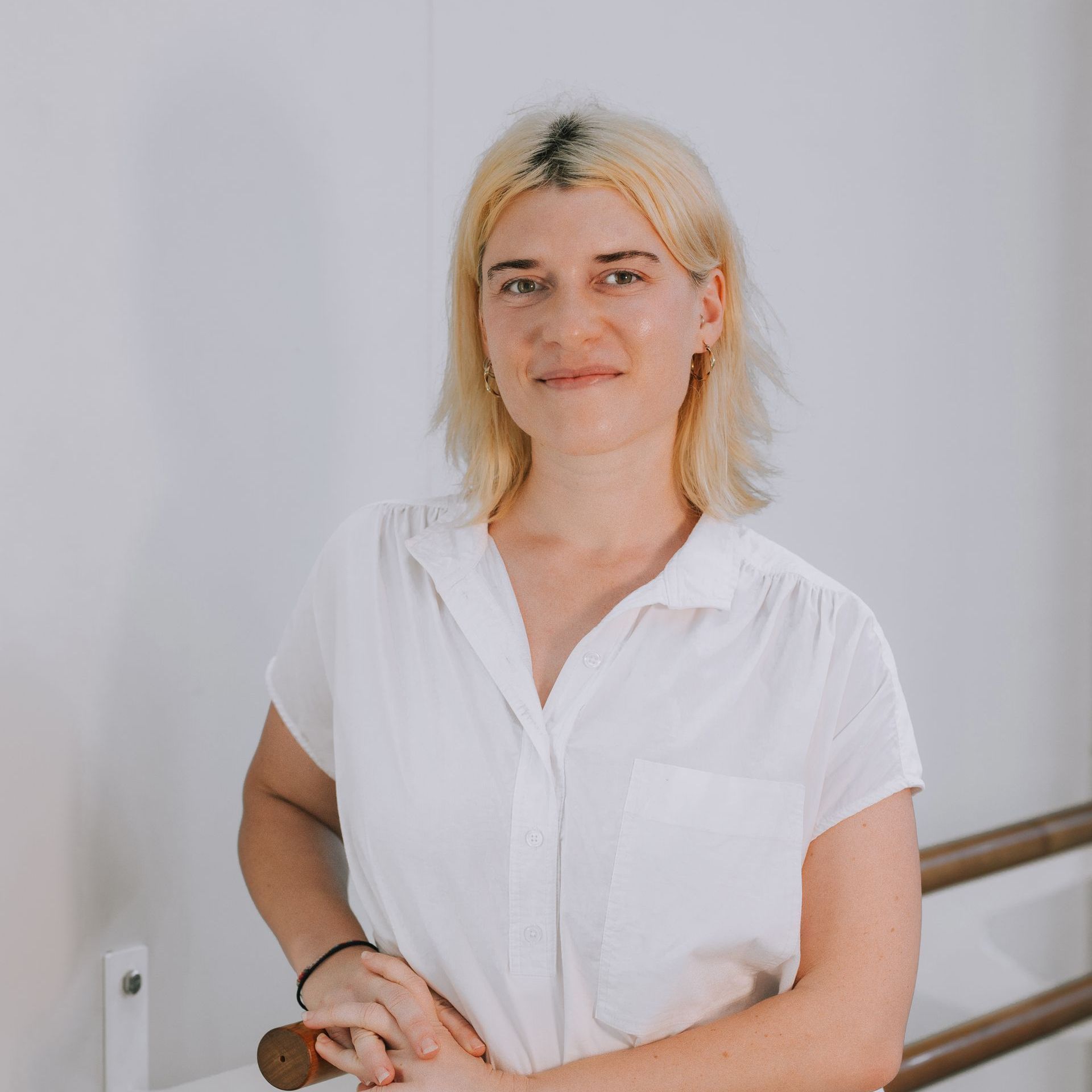 A woman in a white shirt is standing next to a railing.