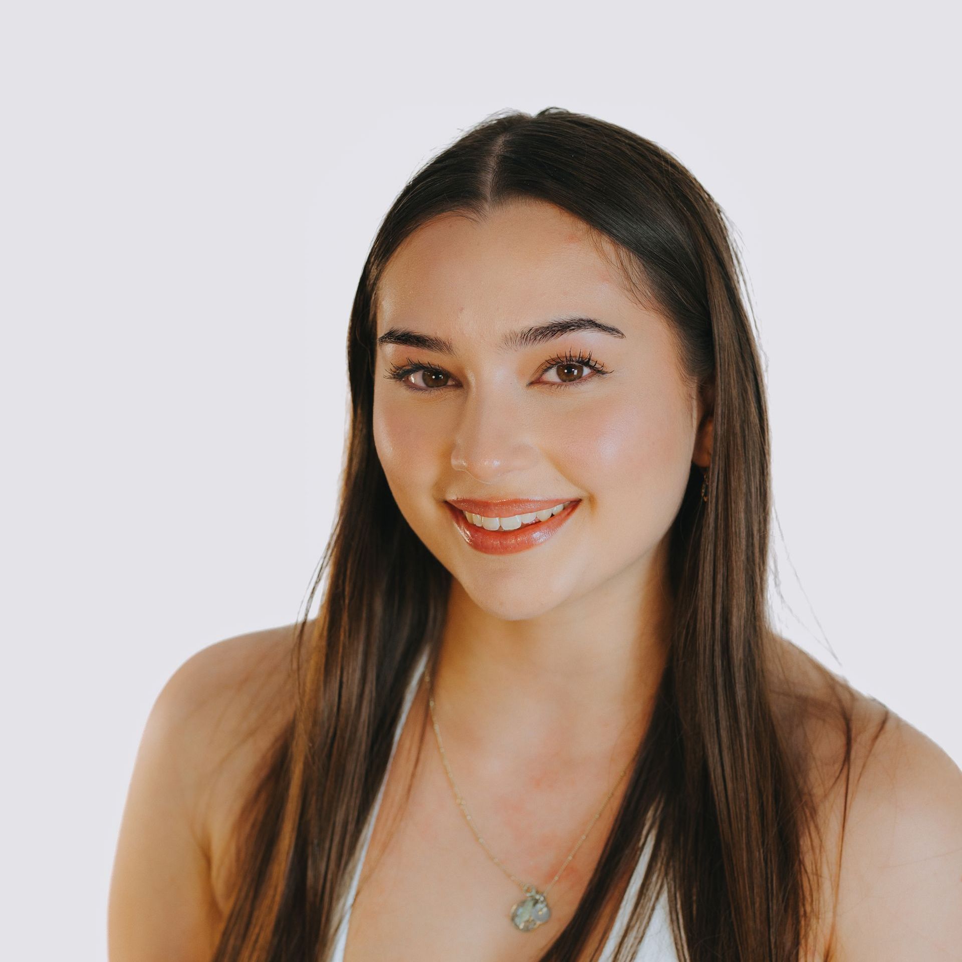 A woman with long hair is smiling and wearing a necklace