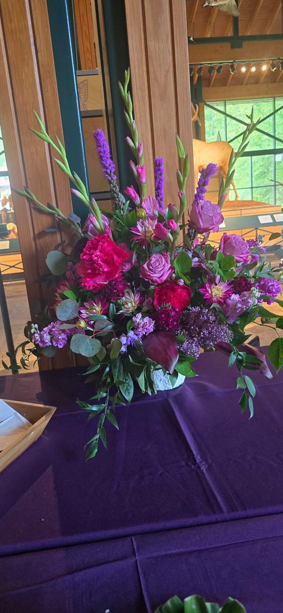A vibrant flower arrangement with pink and purple blooms on a purple tablecloth.