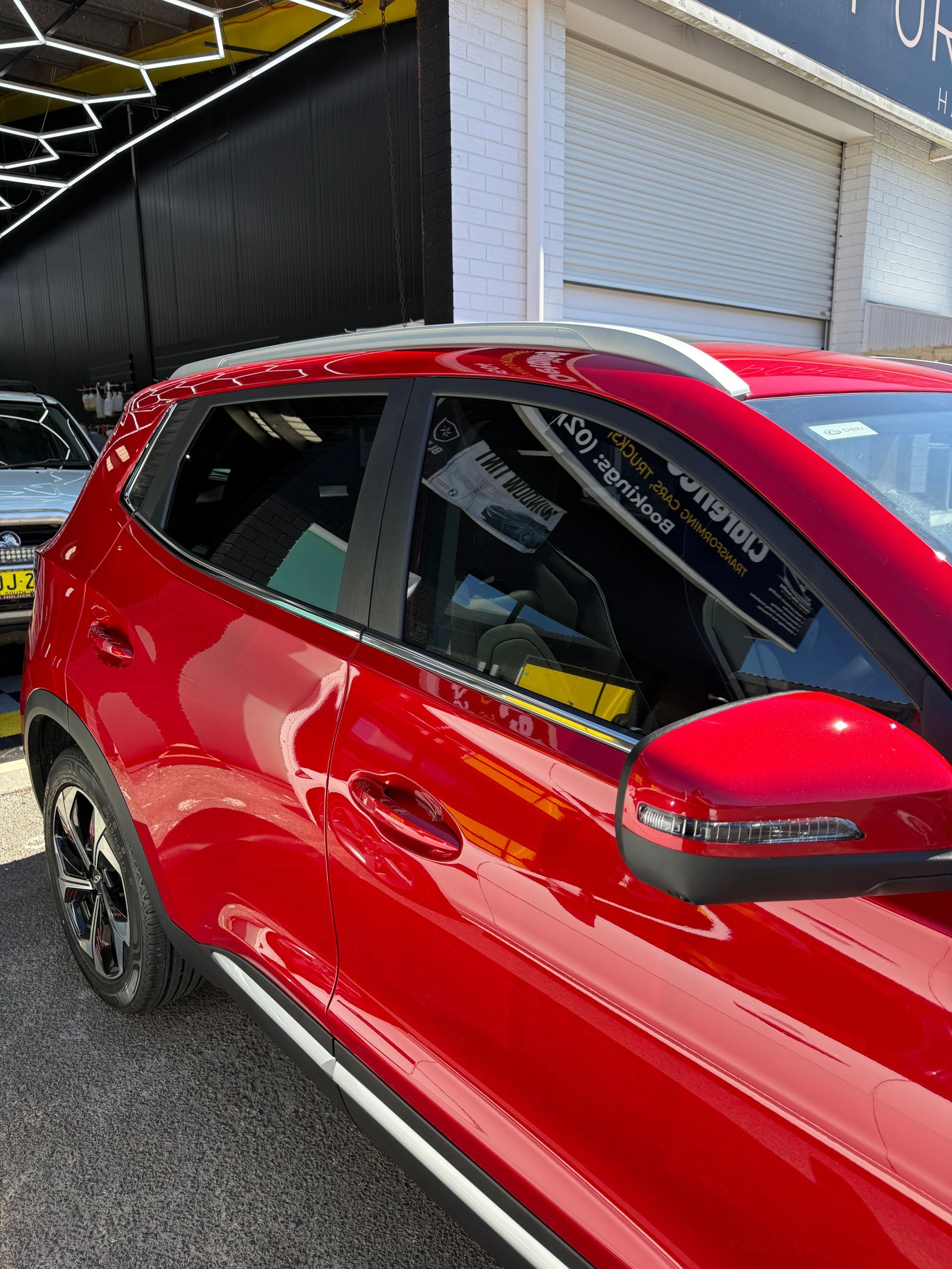 A Red Car is Parked in Front of a Building With Black Tinting— Clarence Valley Detailing In Yamba, NSW