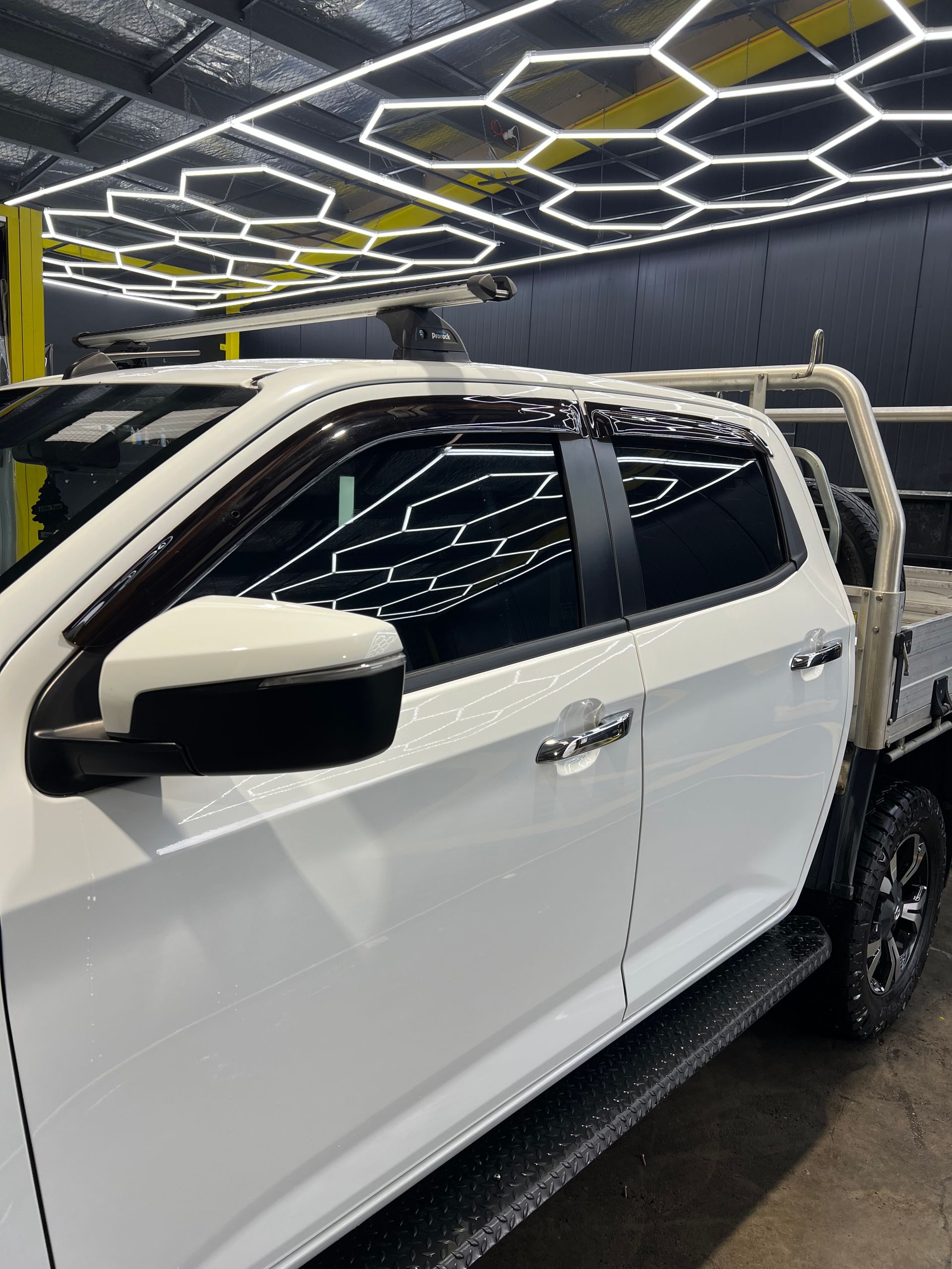A White Ute Car is Parked on a Checkered Floor in a Garage — Clarence Valley Detailing In Yamba, NSW