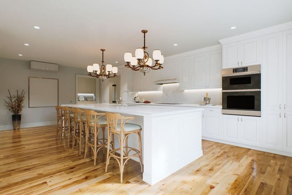 Bright modern kitchen with white cabinets, island seating, and hardwood floors