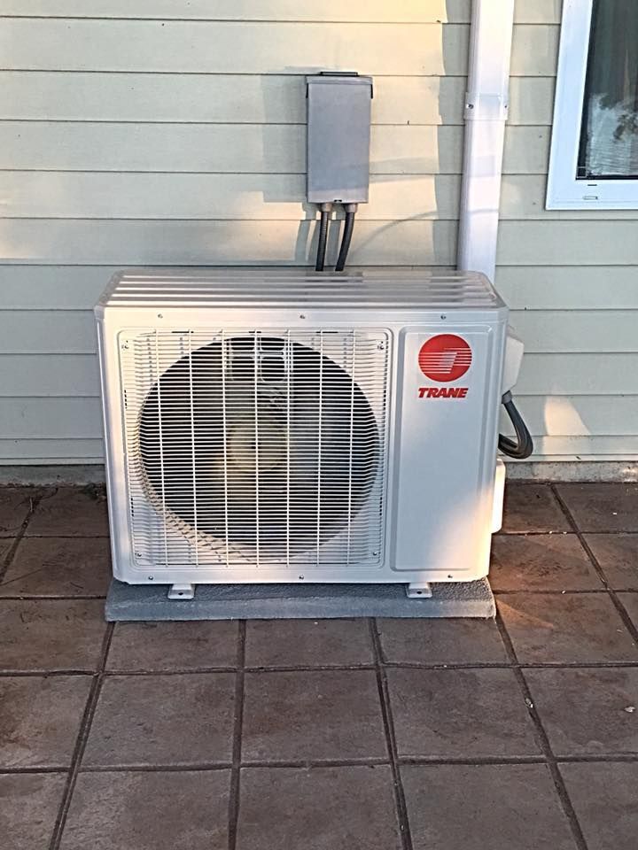 Air Connections Inc - A white air conditioner is sitting on a tiled floor outside of a house.
