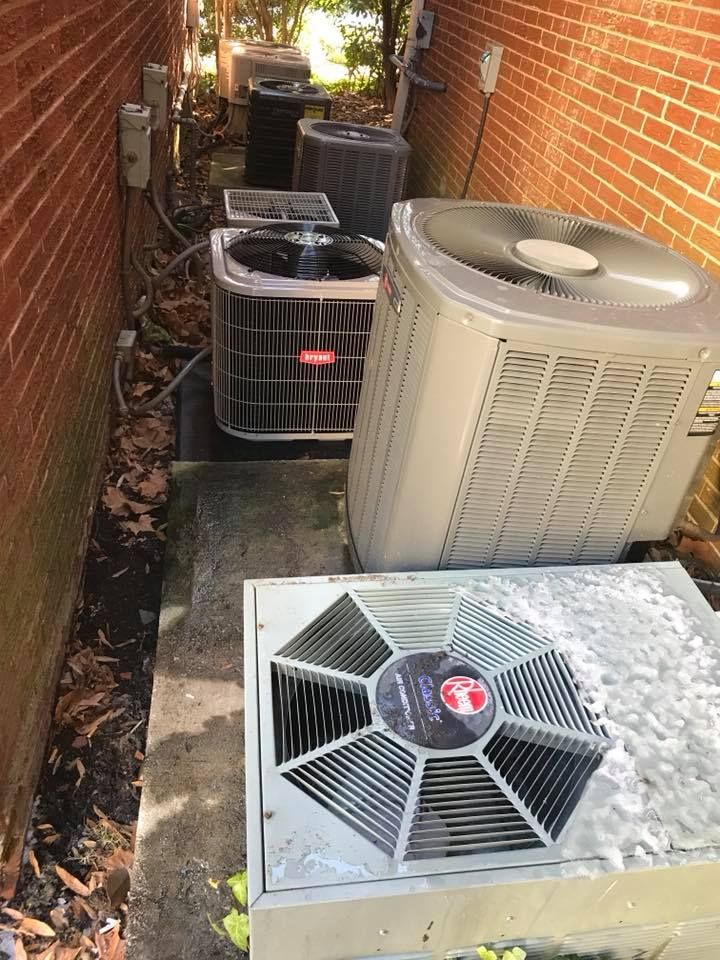 Air Connections Inc - A row of air conditioners are sitting on the side of a brick building.
