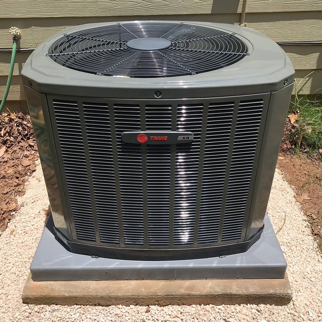 Air Connections Inc - A large air conditioner is sitting on top of a gravel platform.