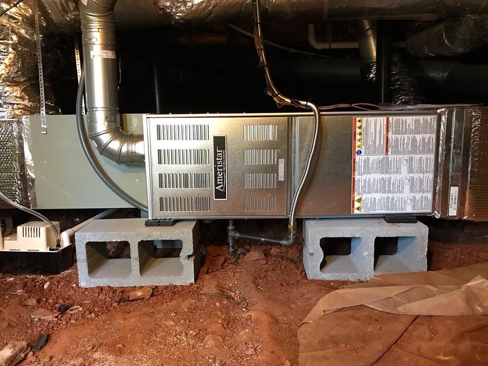 Air Connections Inc - An air conditioner is sitting on top of concrete blocks in a basement.