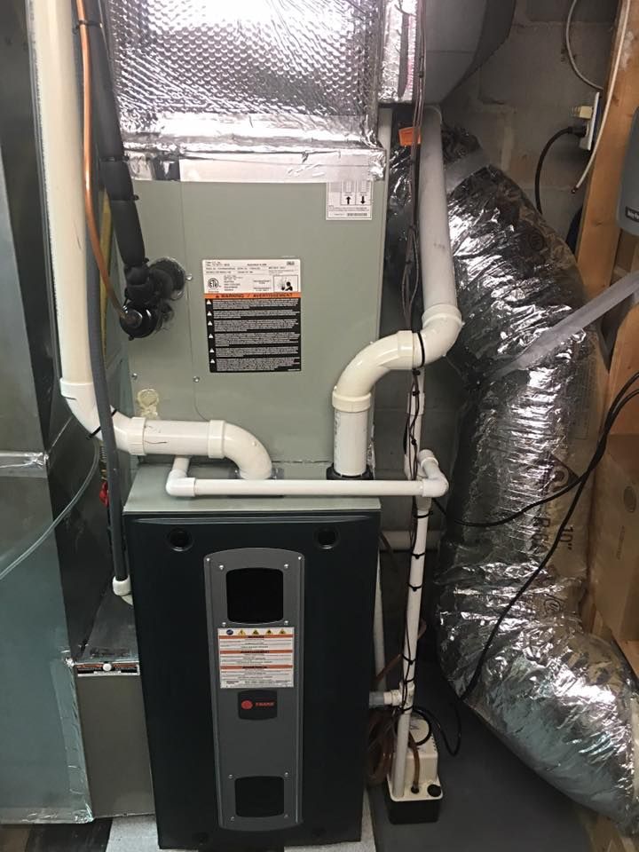 Air Connections Inc - An air conditioner is sitting in a basement next to a pipe.