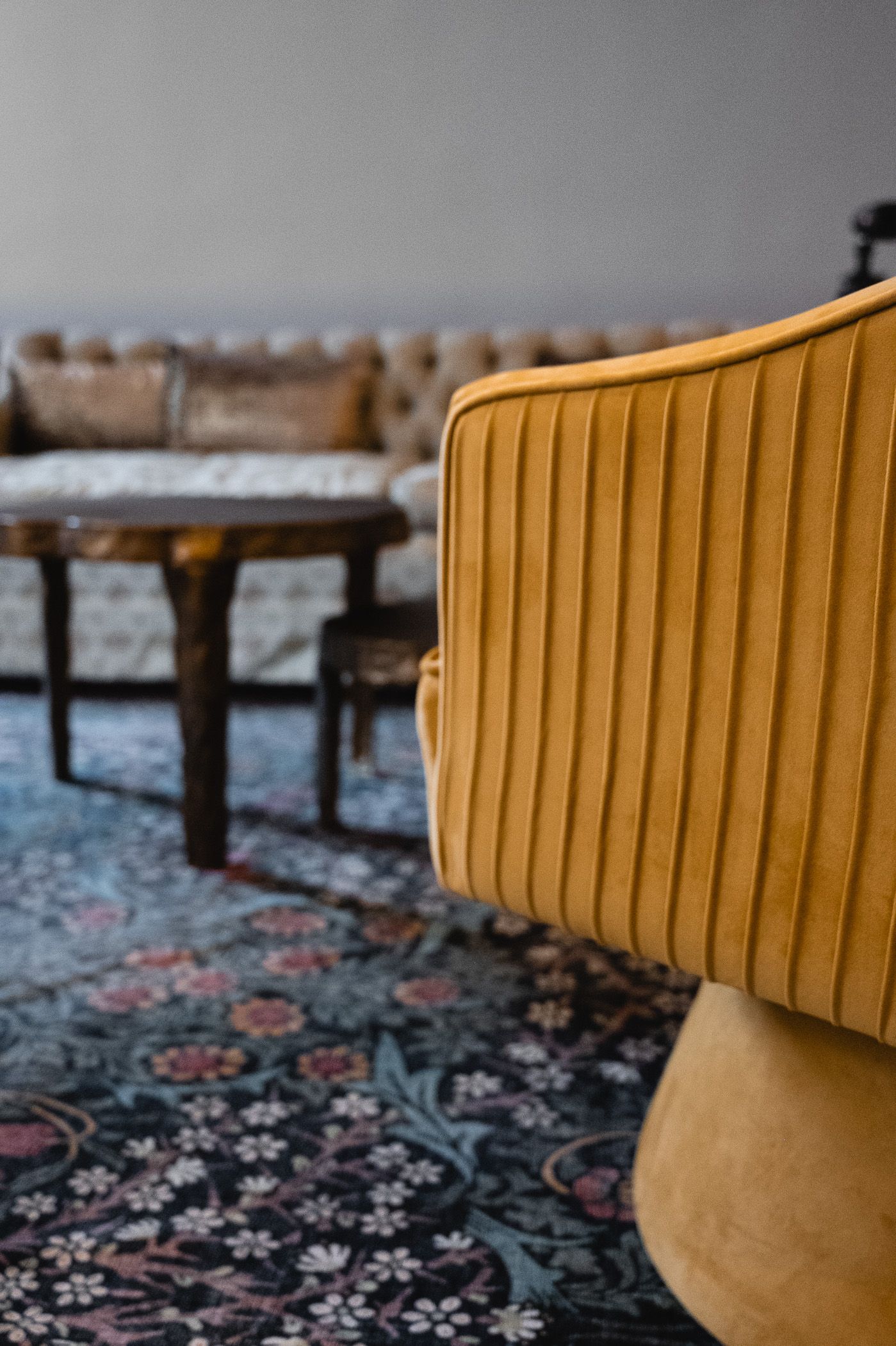 side of yellow plush armchair, dramatic floral rug