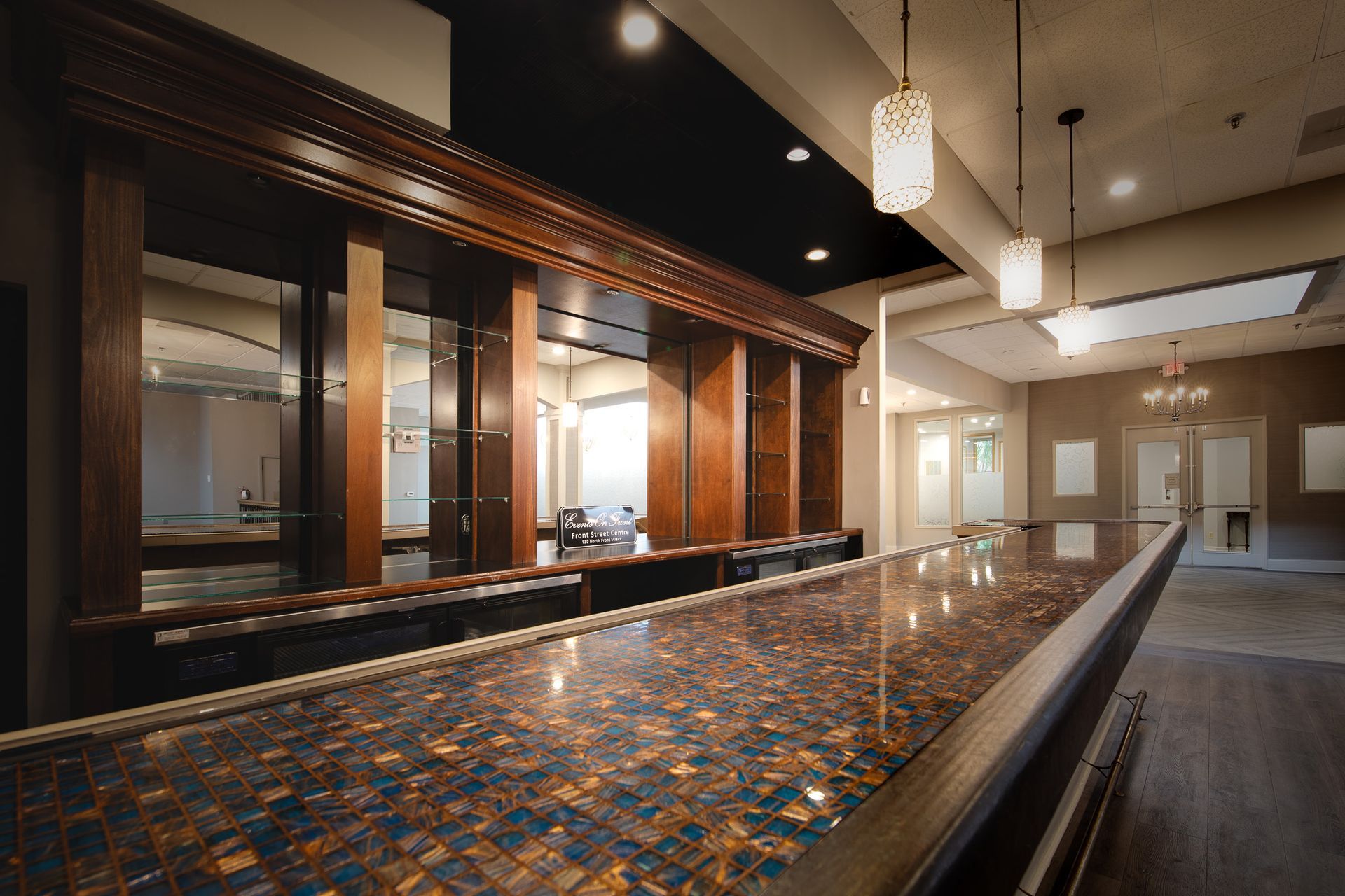 close up of 18 foot tile bar with intricate countertop and mirrors against back wall
