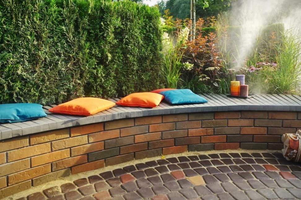 A Brick Wall With Pillows And Candles On It In A Garden — Southern Bricks & Pavers In Batemans Bay, NSW