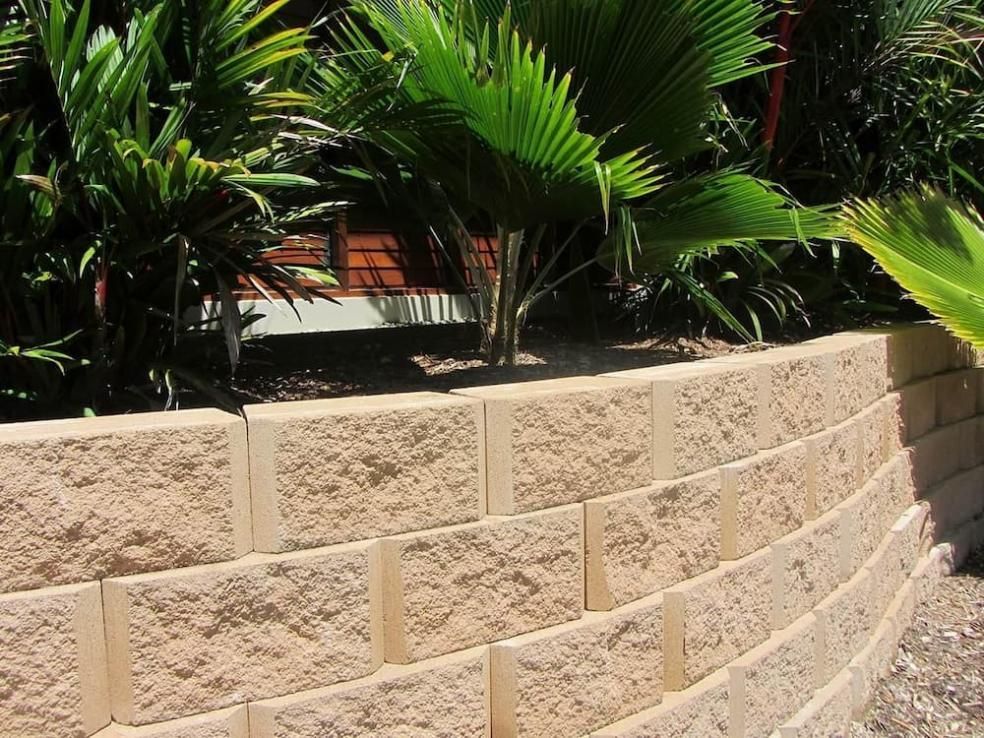 A Brick Wall With Palm Trees In The Background — Southern Bricks & Pavers In Ulladulla, NSW