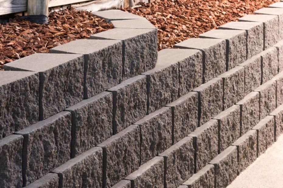 A Brick Wall With A Pile Of Mulch In The Background — Southern Bricks & Pavers In Ulladulla, NSW