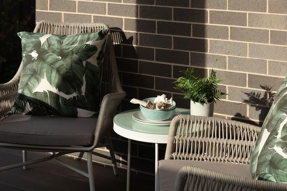 A Patio With Two Chairs And A Table With A Bowl Of Food On It — Southern Bricks & Pavers In Ulladulla, NSW