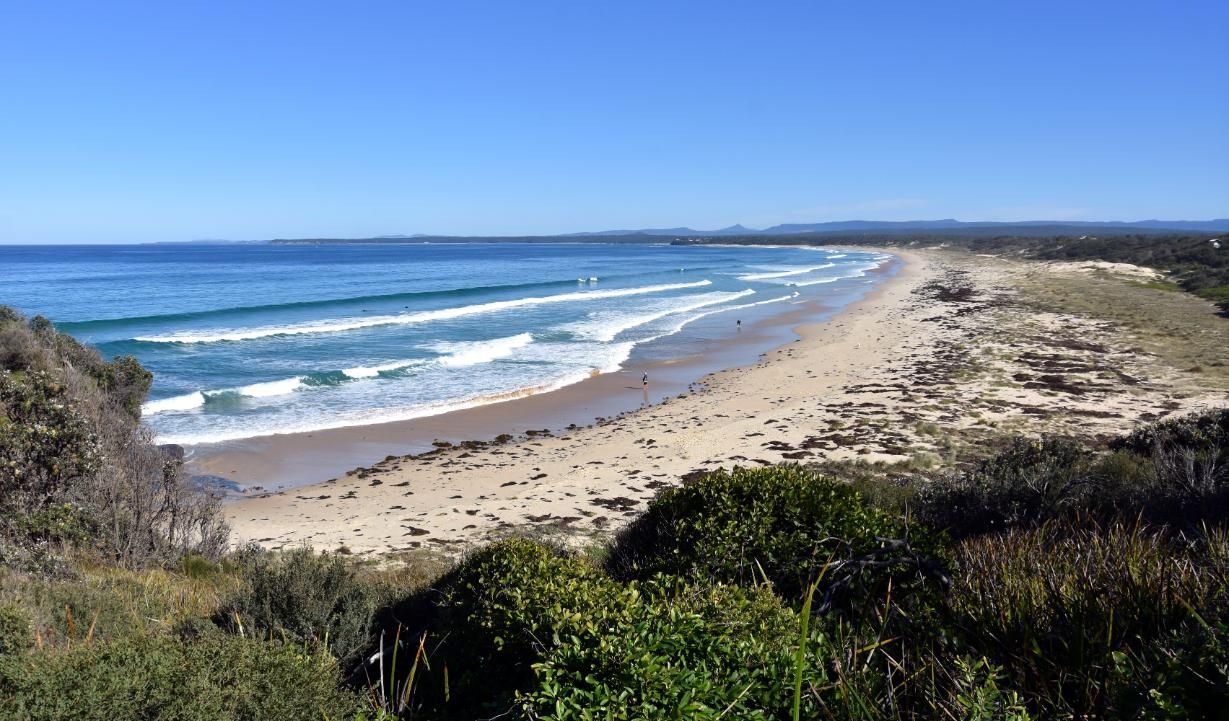 A Beach With A Lot Of Waves Coming In On A Sunny Day — Southern Bricks & Pavers In Sussex Inlet, NSW
