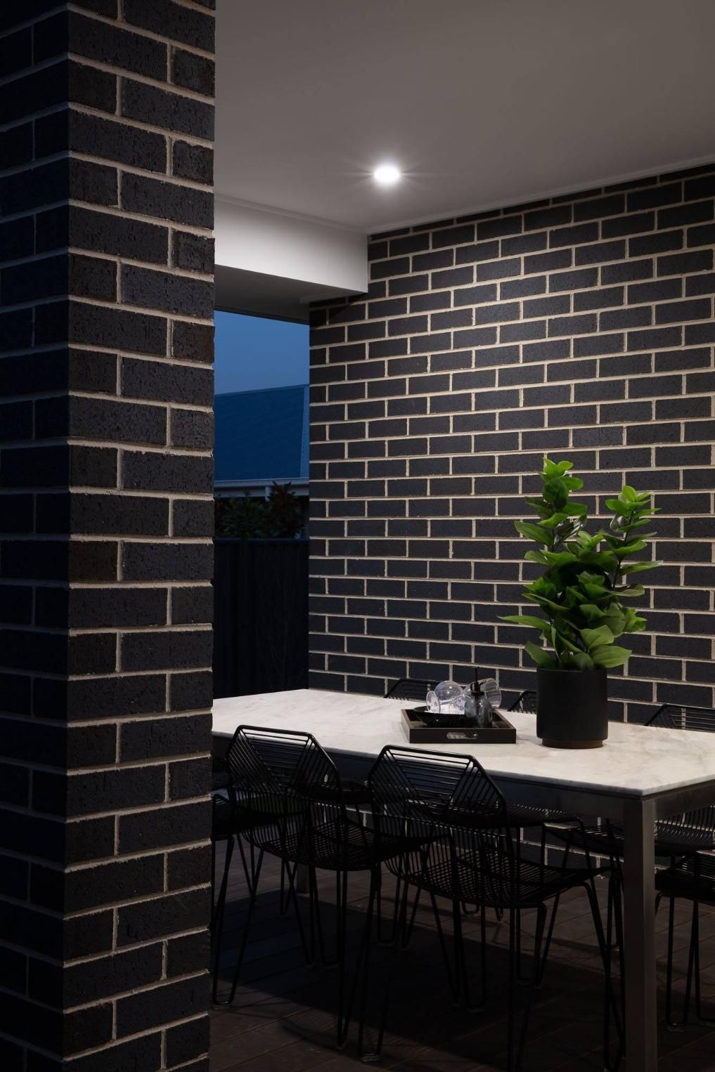 A Dining Room With A Table And Chairs And A Brick Wall — Southern Bricks & Pavers In Batemans Bay, NSW