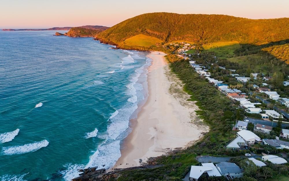 An Aerial View Of A Beach With Houses And Mountains In The Background — Southern Bricks & Pavers In Batemans Bay, NSW