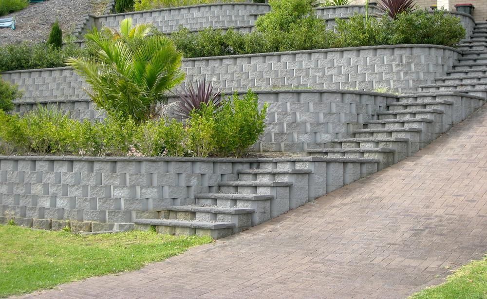 A Stone Wall With Stairs Leading Up To A House — Southern Bricks & Pavers In Sussex Inlet, NSW