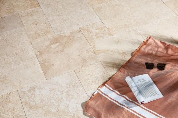 A Towel, Sunglasses, And A Book Are On A Tiled Floor — Southern Bricks & Pavers In Ulladulla, NSW
