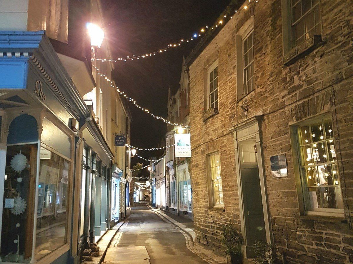 A narrow ancient Cornish street at dusk with garlands of Christmas lights