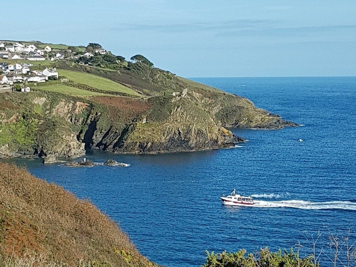 Blue sea and sky at the mouth of Fowey estuary with the red and white Mevagissey ferry heading into harbour