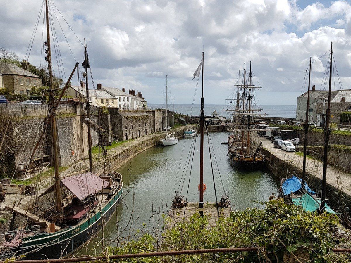 The view down the historic harbour at Charlestown with several tall ships moored along the quayside