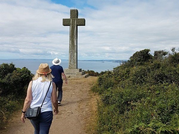Walkers approaching the huge granite cross on Dodman Point with view beyond to distant headlands