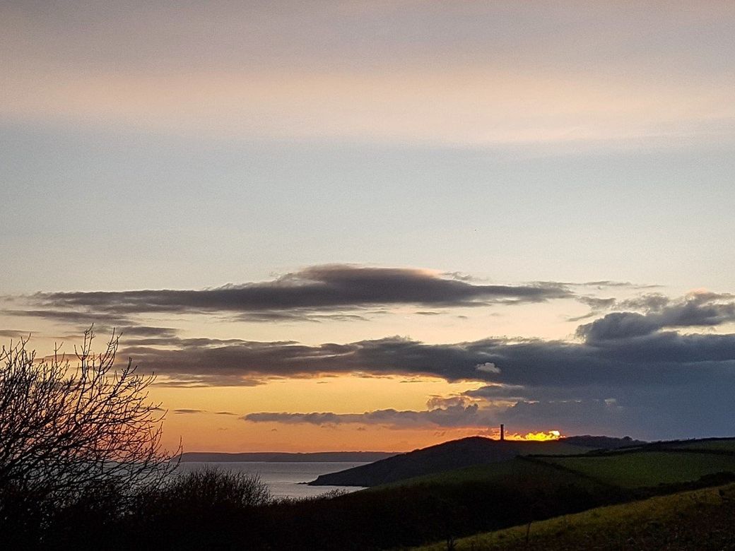 Sunset view of daymark tower, headland and sea with dramatic clouds