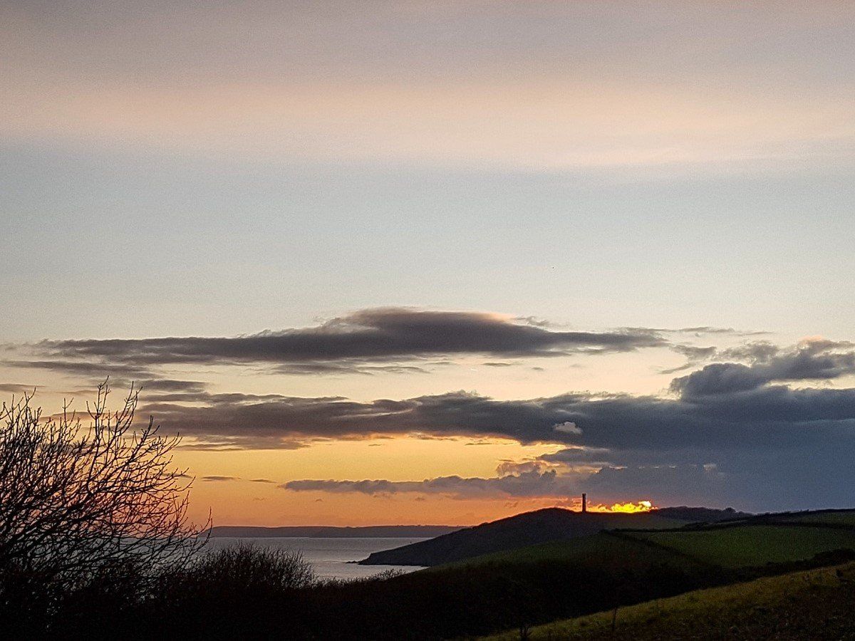 Sunset view of daymark tower, headland and sea with dramatic clouds