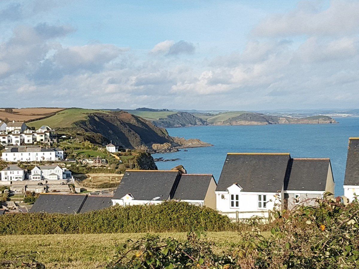 View of Mevagissey village with blue sea and rolling coast beyond