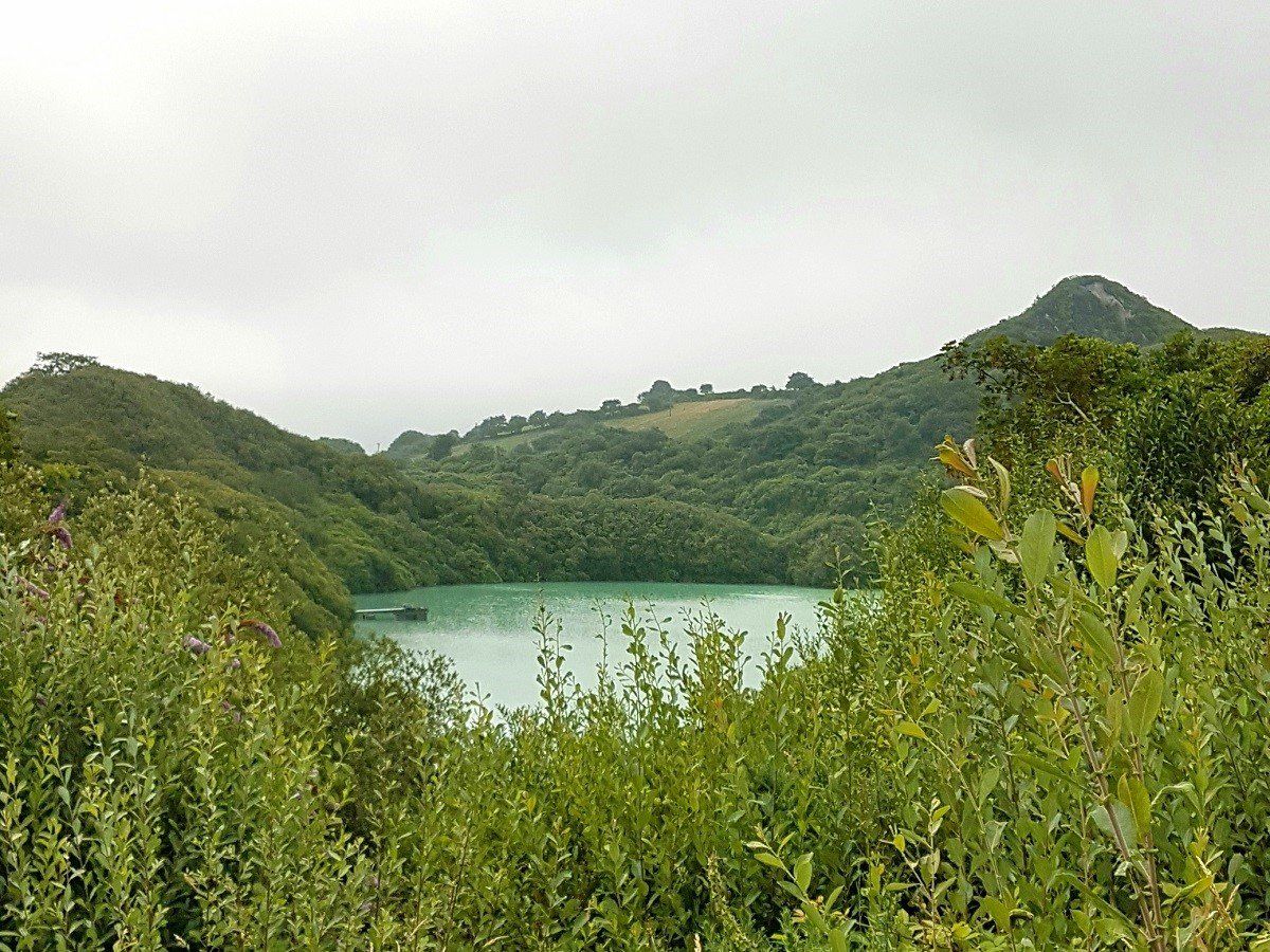 Turquoise lake formed in flooded china clay pit in wooded surrounds