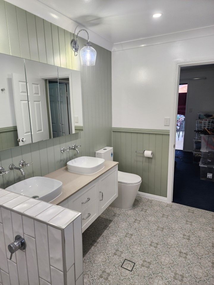 Bright modern bathroom with double vanity, large mirror, toilet, and walk-in shower.