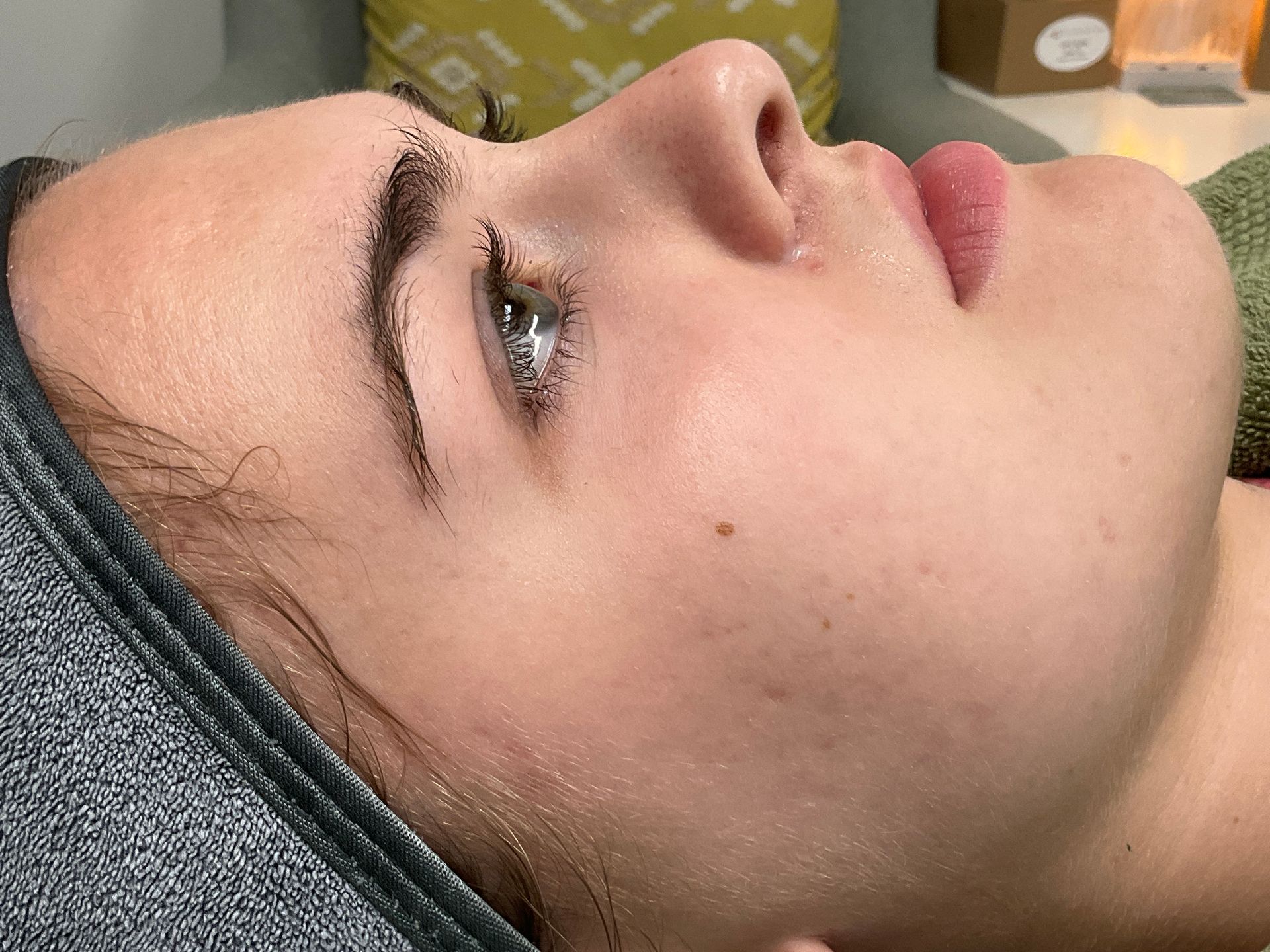 Woman with dewy skin, dark eyebrows, and a spa headband, in profile.