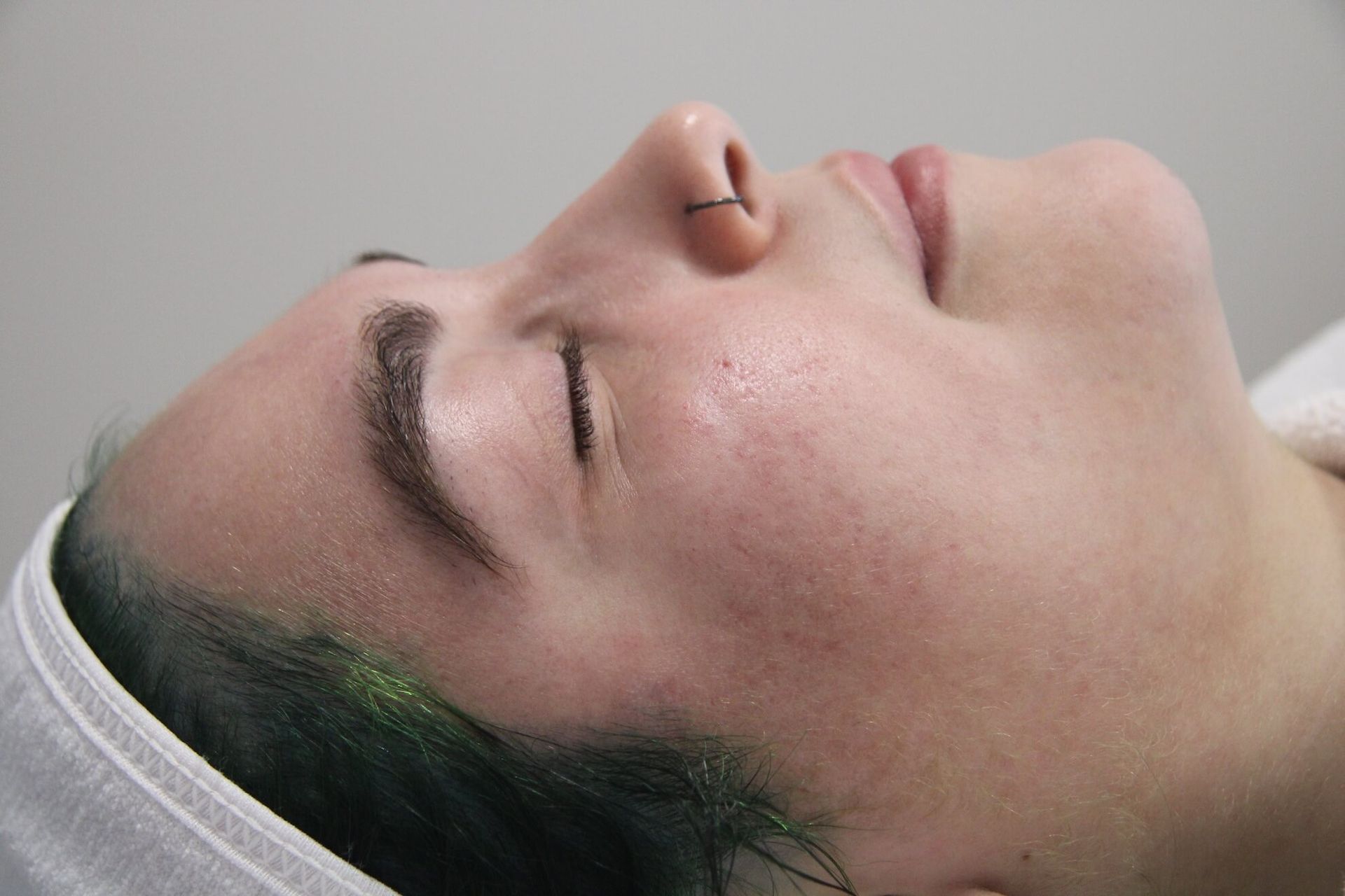 Woman's face in profile, eyes closed. She has fair skin, a small nose ring, and appears relaxed.