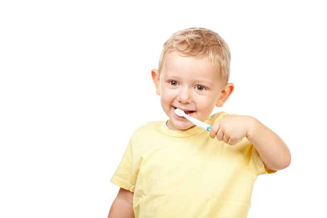 Young child brushing teeth with toothbrush; yellow shirt.