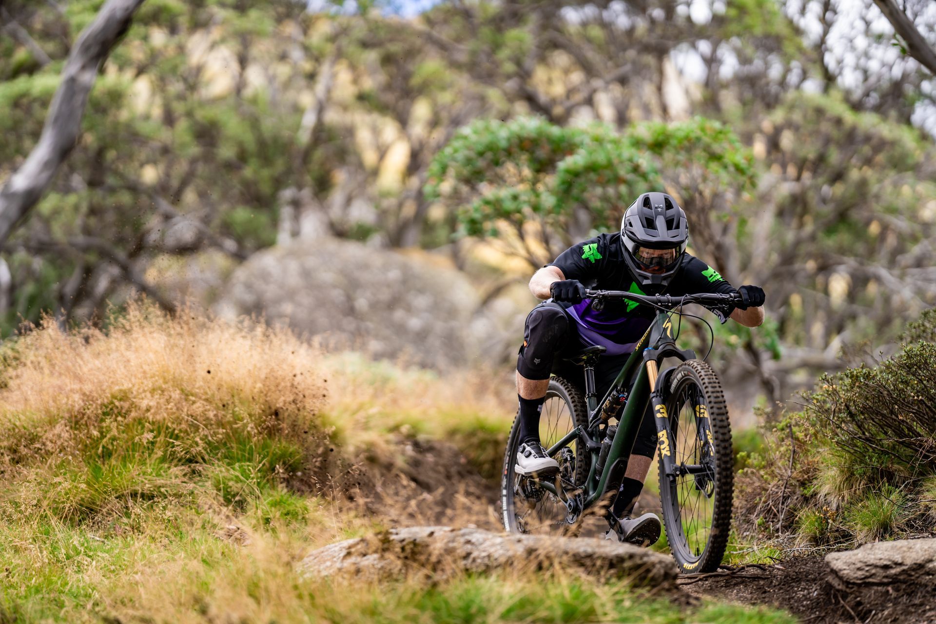 A man is standing next to a mountain bike in a field.