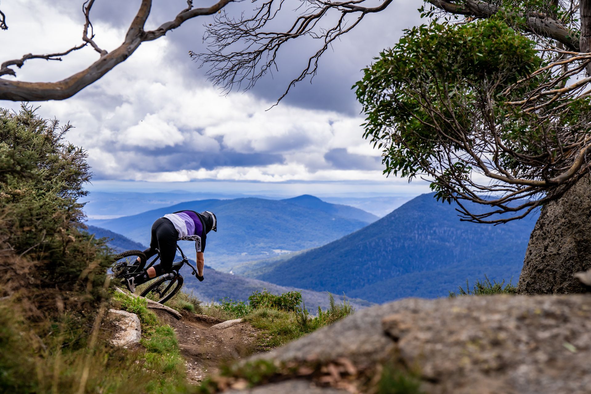 A man is riding a mountain bike down a trail in the mountains.