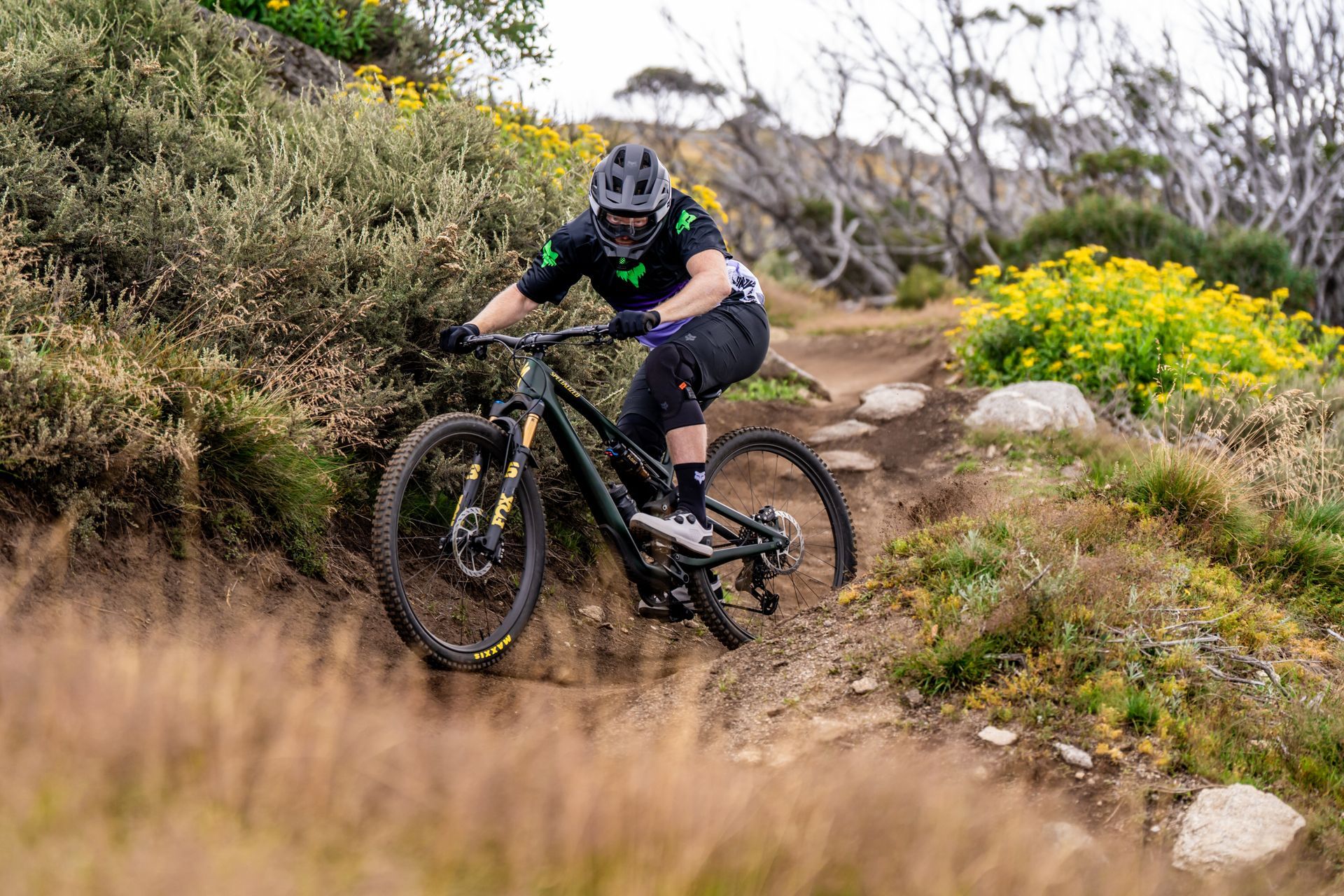 A man is riding a mountain bike down a rocky trail in the woods.