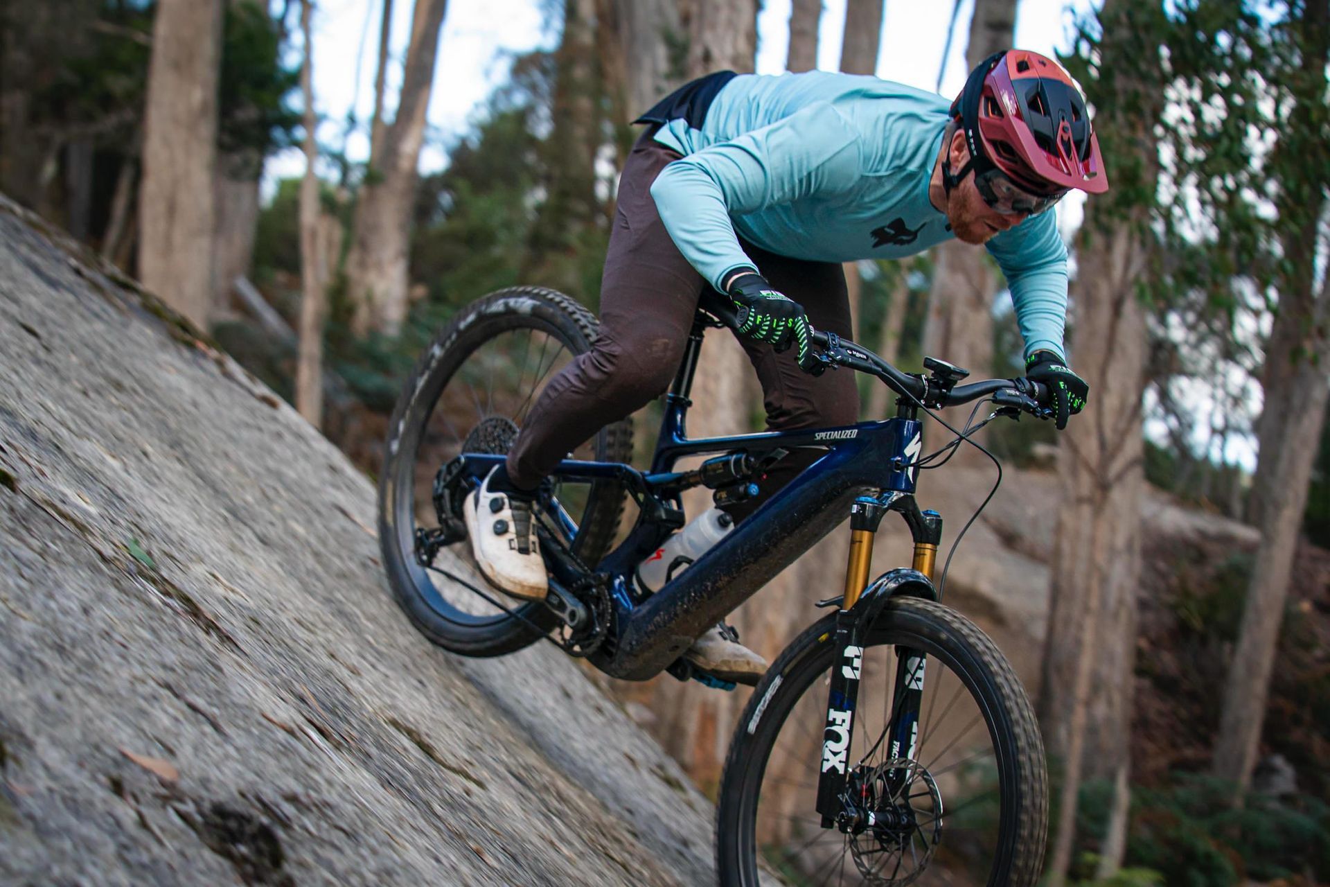 A man is riding a mountain bike down a rocky hill in the woods.
