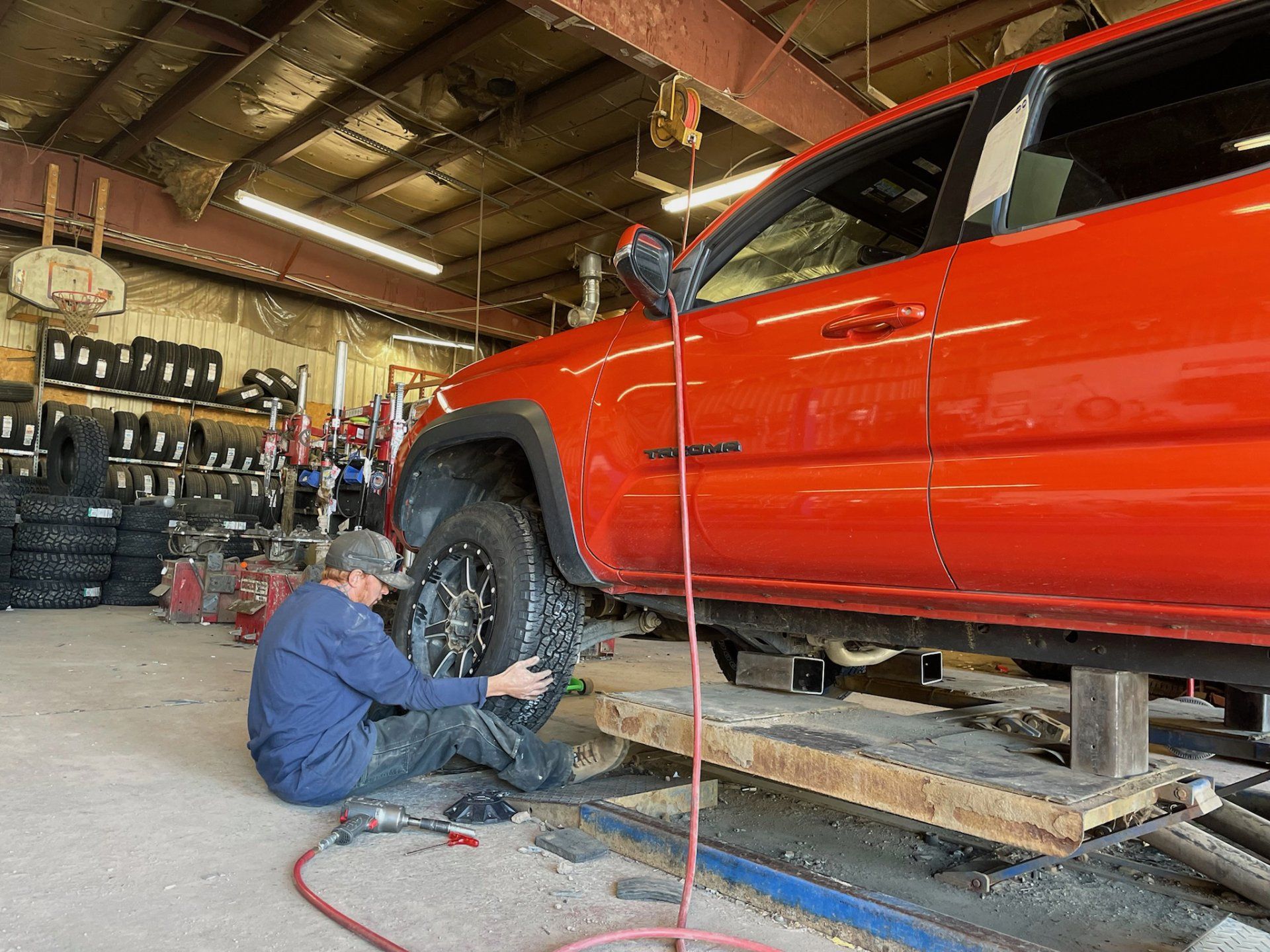 man changing tire on orange toyota
