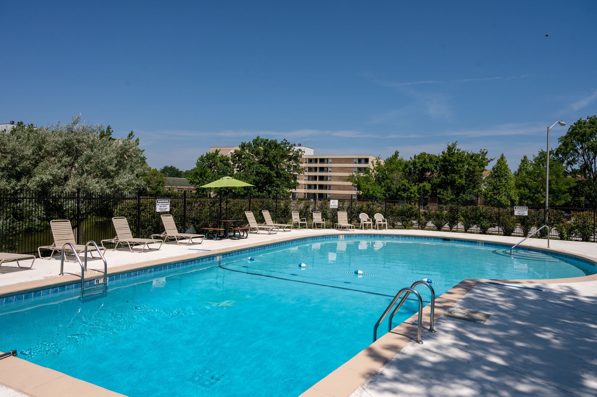 Aerial view of apartment buildings with parking, a road, and a green field.